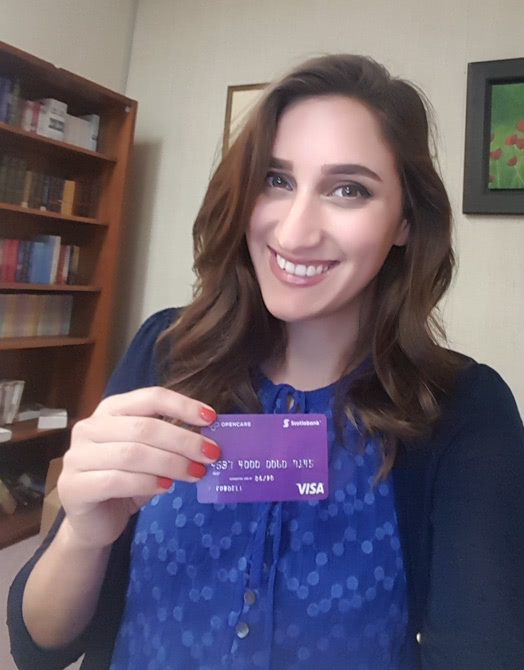 Young girl smiling brightly holding an Opencare visa giftcard