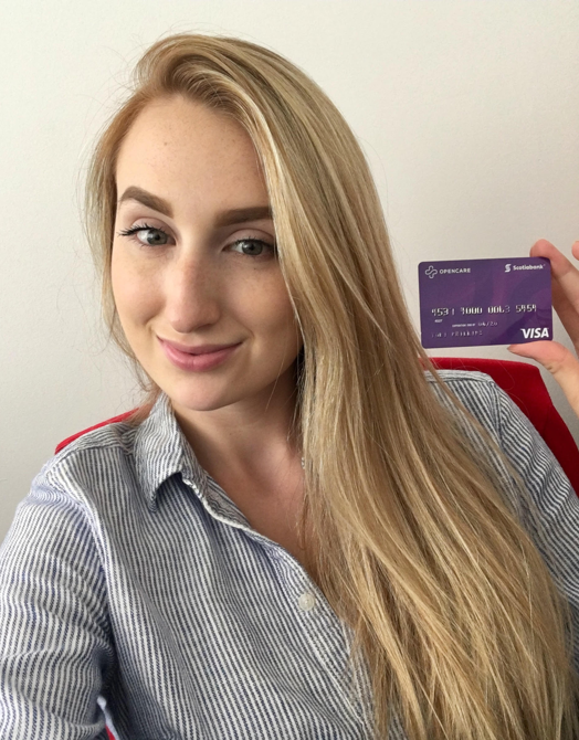 Young girl smiling brightly holding an Opencare visa giftcard